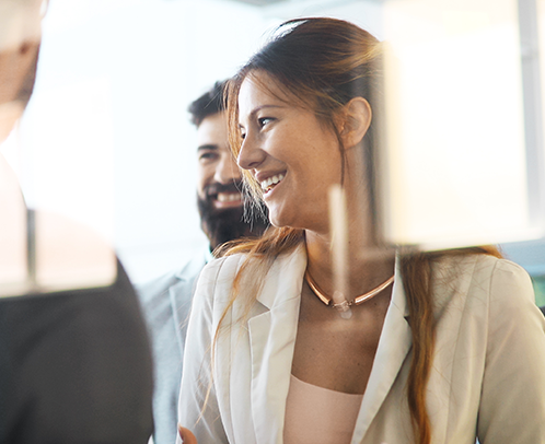 A professional woman, in an office, smiling at colleagues