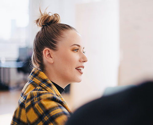 A close up of professional looking woman in a yellow checkered jacket looking engaged in conversation